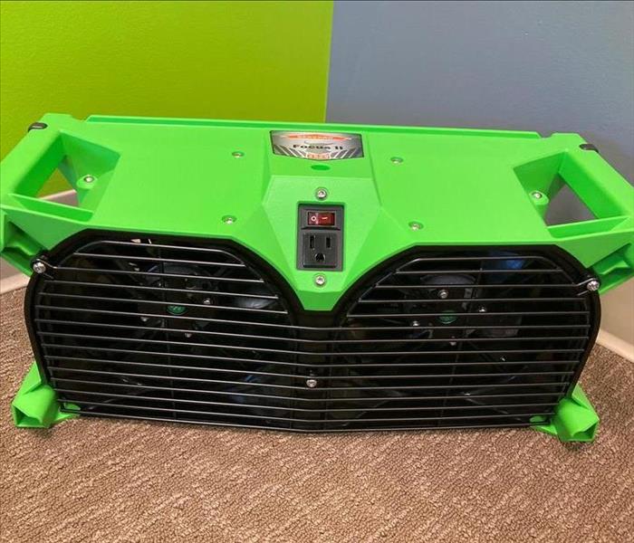 Close-up picture a SERVPRO branded Focus II Air Mover machine against a green and gray background.