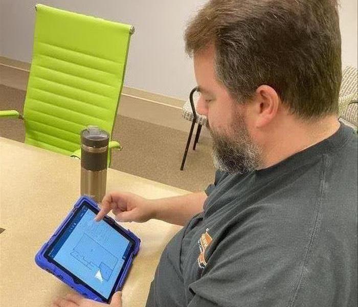 Brown haired man with beard using an iPad to create estimates